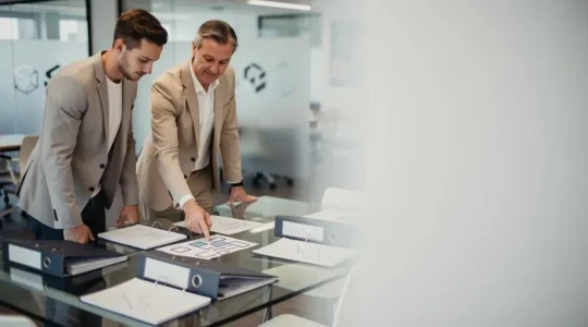 Un fondateur de startup et un auditeur examinant ensemble des documents abstraits lors d'un audit de conformité assurantielle avant une levée de fonds