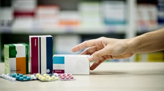 Boîtes de médicaments floutées sur un comptoir de pharmacie évoquant le reste à charge et le remboursement